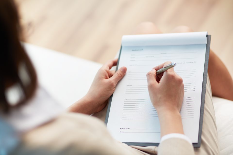 A woman fills out a form with a pen