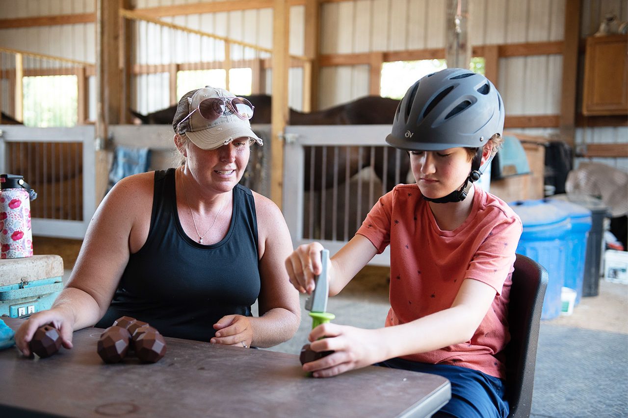 young boy performing an activity with a therapist during a hippotherapy session