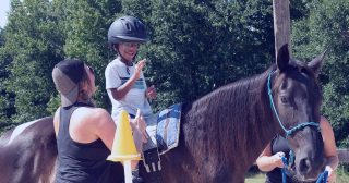 A young boy on horseback is assisted by two therapists during a hippotherapy session at Carolina Therapeutic Ranch in Rock Hill, SC