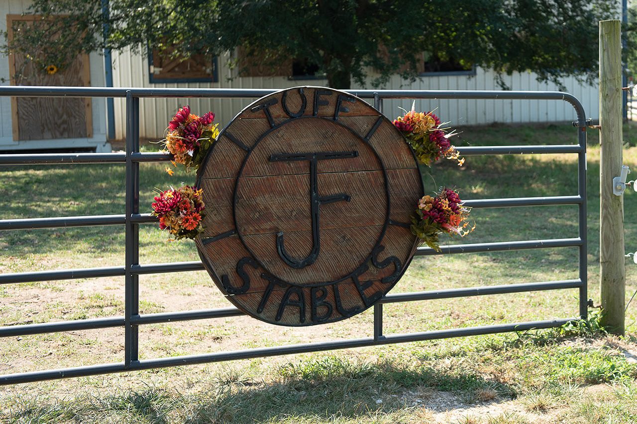 Round wooden sign on entry gate of JF Tuff Stables in Rock Hill, SC