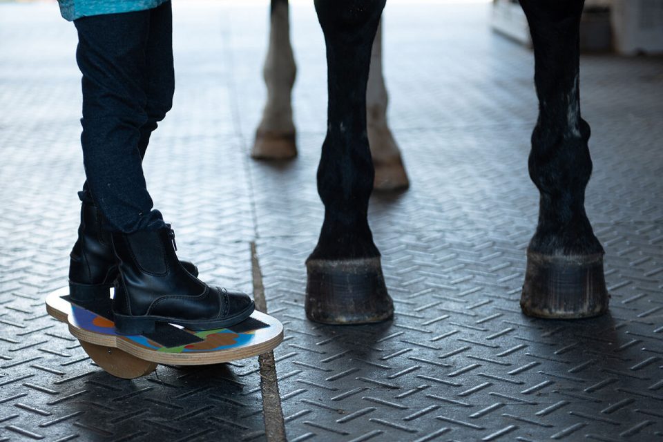 Legs of a horse and a small child in a barn